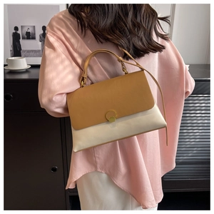 Detail of color-block leather handbag in brown and cream with a round metal clasp
