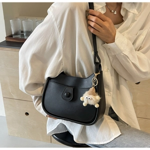 Close-up of black PU leather bucket bag with a cute white plush monster pendant