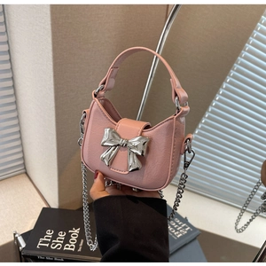 Detail of pink leather mini bag featuring silver bow buckle and detachable chain strap