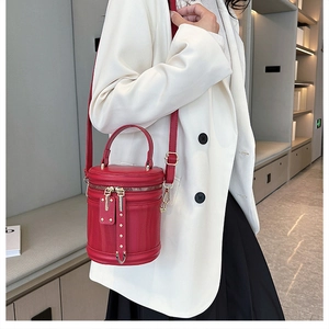 Red cylindrical bucket bag with vertical stitching details and golden hardware on a model