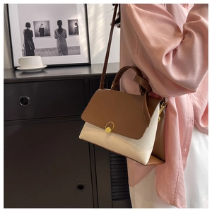 Detail of two-tone shoulder bag with brown flap, white body and gold ring magnetic clasp