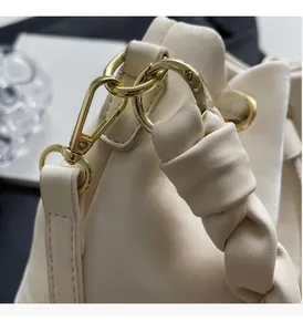 Detail of cream leather handbag featuring thick knotted handle and gold metal hardware