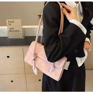 Close-up of a pale pink matte leather underarm bag with a cute heart pendant detail