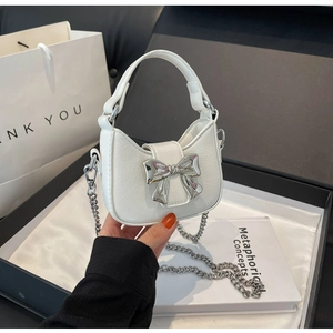 Detail of white wrinkled PU leather mini bag with silver bow accent and chain strap