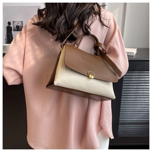 Detail showing the contrast leather flap and gold ring closure on the beige shoulder bag