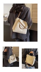 Close-up of beige woven texture and leather handle on a large capacity bucket bag