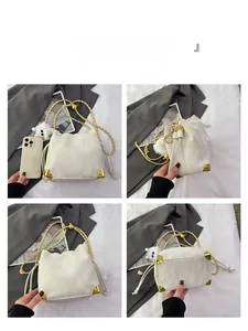 Dettagli di una borsa a secchiello bianca a pieghe con catena dorata e angoli in metallo