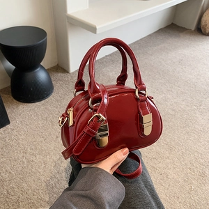 Glossy red patent leather bowling bag with gold hardware and adjustable crossbody strap