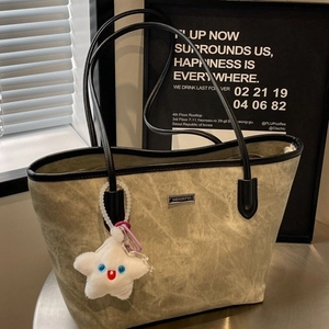 Olive green tote bag with black trim and star plush charm on a minimalist background