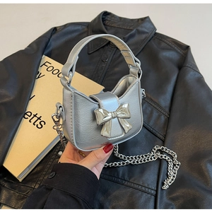 Detail of silver metallic handbag with large bow ornament and long chain strap