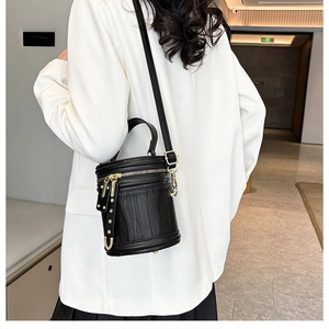 Detail of black cylinder bucket bag with vertical texture and gold metal hardware