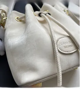 Detail of cream white bucket bag showing soft textured fabric and gold metal drawstring rings