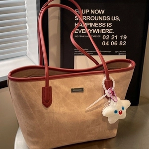 Large beige suede tote bag with red leather straps and star charm for stylish commuting