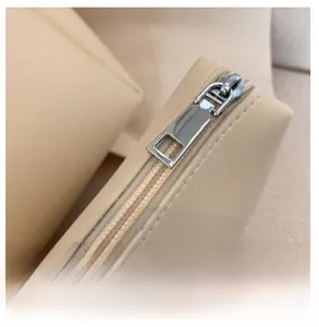 Close-up of smooth silver zipper detail on a beige textured leather tote bag