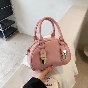 Pink glossy patent leather bowling bag with gold hardware and curved silhouette