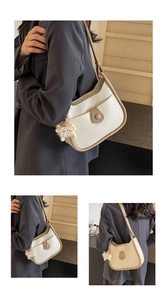 Detail of cream leather shoulder bag with brown trim and cute plush monster charm accessory