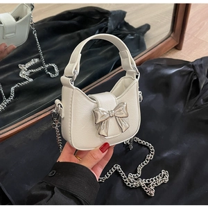 Close-up of white PU leather mini bag with silver bow detail and metal chain strap