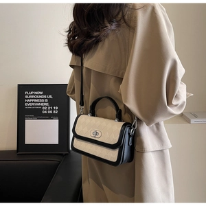Detail of crossbody bag featuring beige quilted pattern with black leather trim and lock