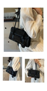 Detail of vintage black underarm bag with cracked texture and slim dual shoulder straps