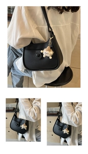 Detail of black leather hobo bucket bag with small pocket and cute plush monster charm