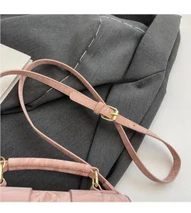 Detailed close-up of pink textured leather handbag with gold metal hardware and strap