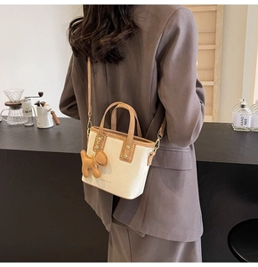 Détail du sac seau bicolore crème et marron avec pendentif chien en décor café