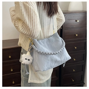 Détail du sac seau plissé bleu clair avec poignée tressée et breloque en peluche