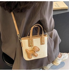 Vue détaillée d'un mini sac cabas avec pendentif chien et finitions marron dans un décor doux