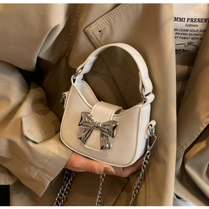 Detail view of the silver metallic bow buckle and textured leather on a chic handbag