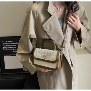 Detail of contrast color quilted small square bag with silver turn-lock and leather strap