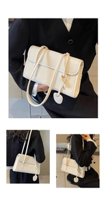 Detail view of cream leather underarm bag with double straps and heart charm accessory
