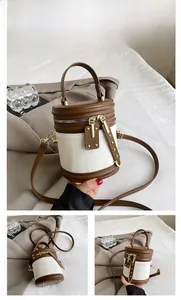 Detail of a brown and cream cylindrical bucket bag with textures and metal zippers