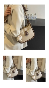 Detail of beige and brown semi-circle leather bag with a white plush sheep charm pendant