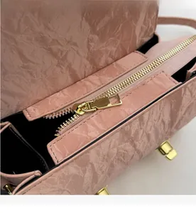 Detail of pink textured leather handbag showing smooth gold zipper and refined interior lining