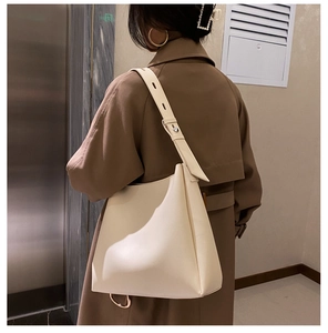 Detail of a large cream soft leather tote bag with wide strap on a model shoulder