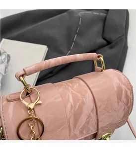 Detail of pink cylindrical handbag with marble texture and golden hardware accents