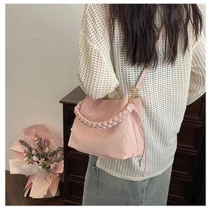 Détail du sac seau plissé rose clair avec poignée tressée et bandoulière fine
