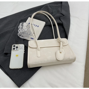 Close-up of minimalist cream underarm bag with a leather texture on a grey blazer