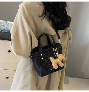 Détail d'un mini sac seau plissé noir avec pendentif chien et accents dorés chic