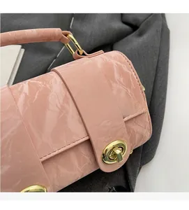Detail of pink textured leather handbag with polished gold rotary clasp and metal hardware