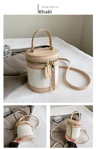 Detail of khaki and white cylinder bag with gold studs and dual-zipper closure