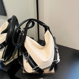 Sac bandoulière croissant noir et blanc avec fermetures éclair sur une surface élégante