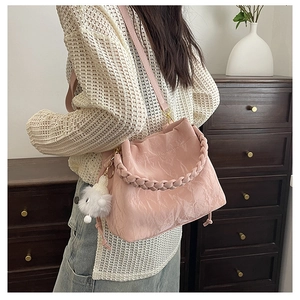 Détail du sac seau rose plissé avec poignée tressée et breloque en peluche douce