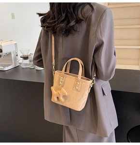 Sac seau beige chic avec breloque chien et bandoulière en métal dans un café minimaliste
