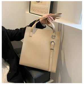 Chic beige soft faux leather tote bag being carried by a model in a minimalist setting
