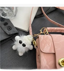 Detail of pink marble-textured crossbody bag with luxury gold lock and plush monster charm
