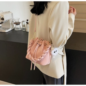 Pink drawstring bucket bag featuring a woven strap detail and cute white plush charm