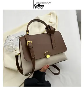 Close-up of contrast brown leather handbag with round metal lock and shoulder strap