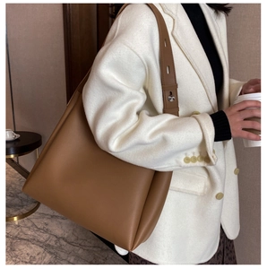 Detail of caramel leather tote bag showing wide shoulder strap and metal buckle adjustment