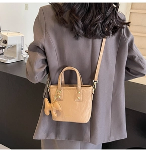 Détail du sac cabas marron clair avec lettrage de mode et pendentif chiot mignon